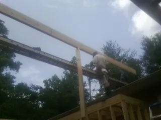 Carpenter setting a ridge beam over a new addition frame — Ice Dam Removal by Roofing Brothers in Martelle