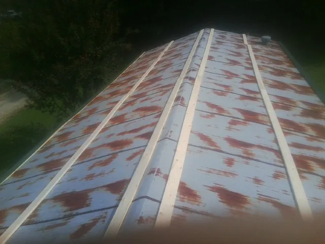 Rusted metal roof panels with new wood purlins before replacement — Storm Damage Roof Repair in Martelle by Roofing Brothers
