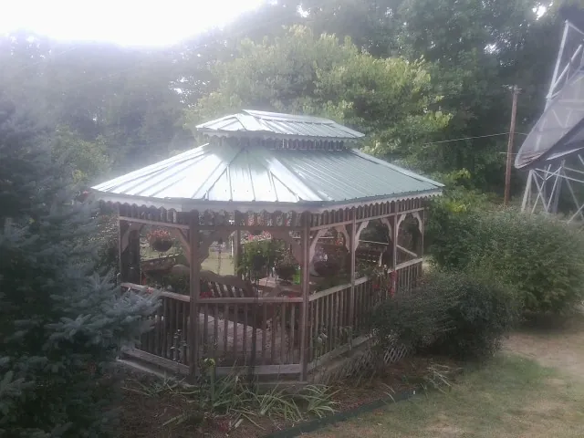 Green metal roof on a backyard gazebo surrounded by garden beds in Martelle