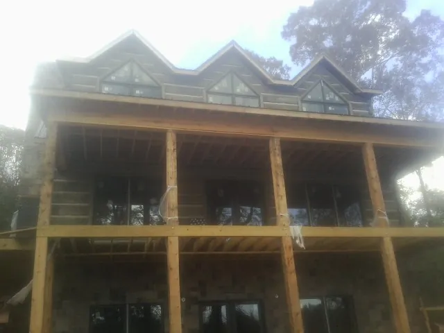 Dormers and porch framing on a large log home under construction — Roof Coating work by our crew in Martelle