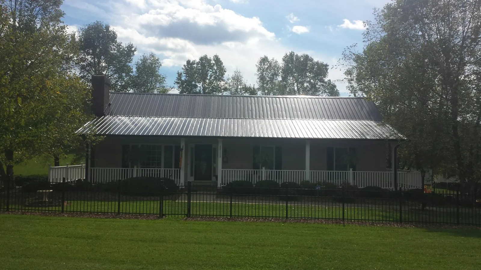 Gray metal roof on a brick ranch with a full width front porch — Gutter Guard Installation work by our crew in Martelle