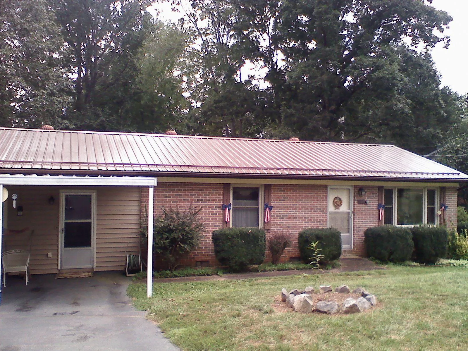 Bronze metal roof and carport on a brick ranch home — Roof Repair work by our crew in Martelle