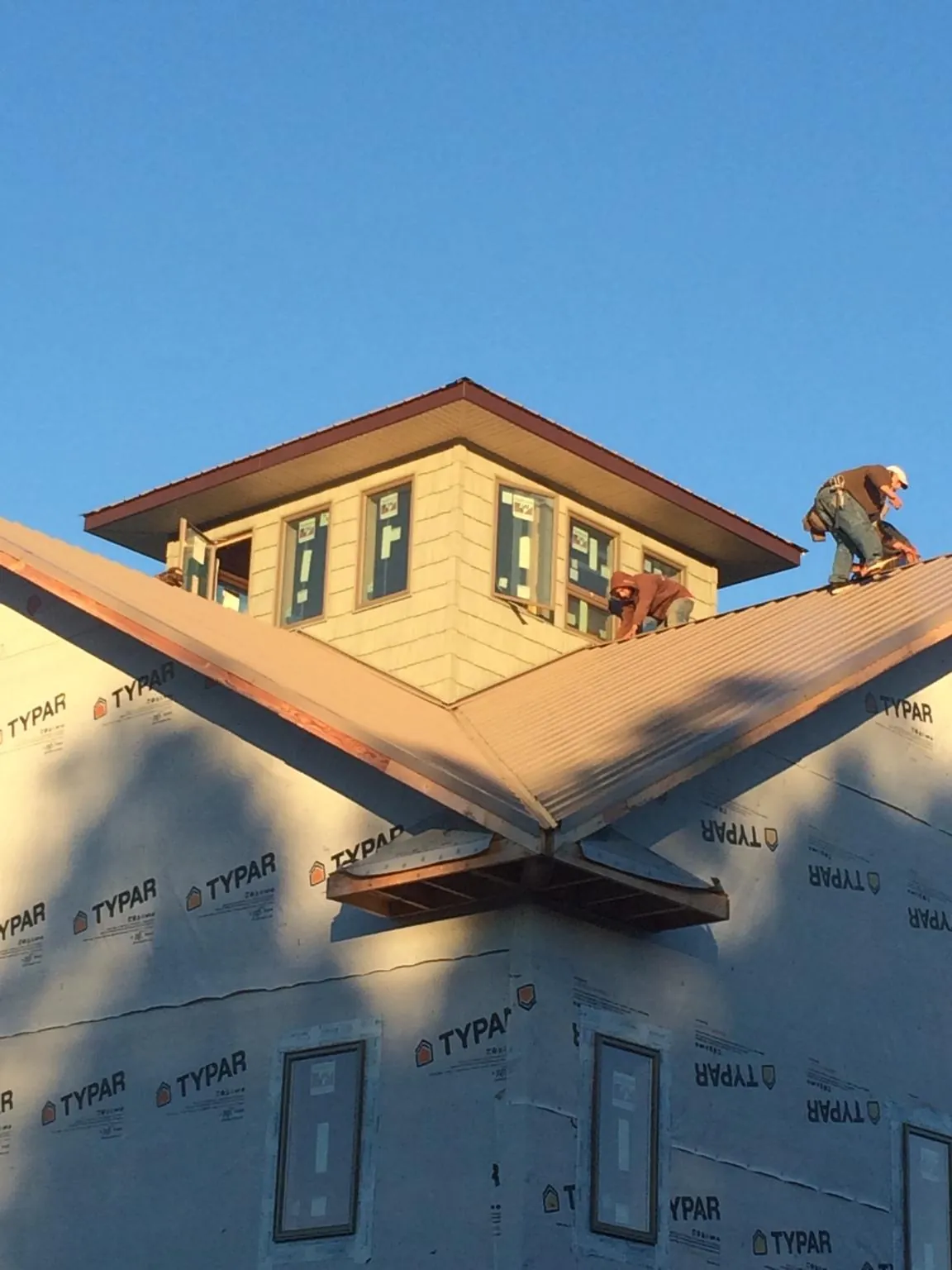 Roofers working around a rooftop cupola on a new metal roof at sunset — Roof Waterproofing in Martelle by Roofing Brothers